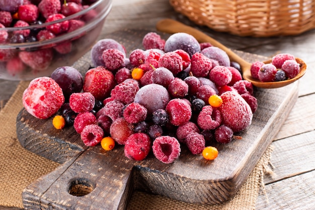 Premium Photo | Mix of different frozen berries on a cutting board on wooden table. frozen food. food storage